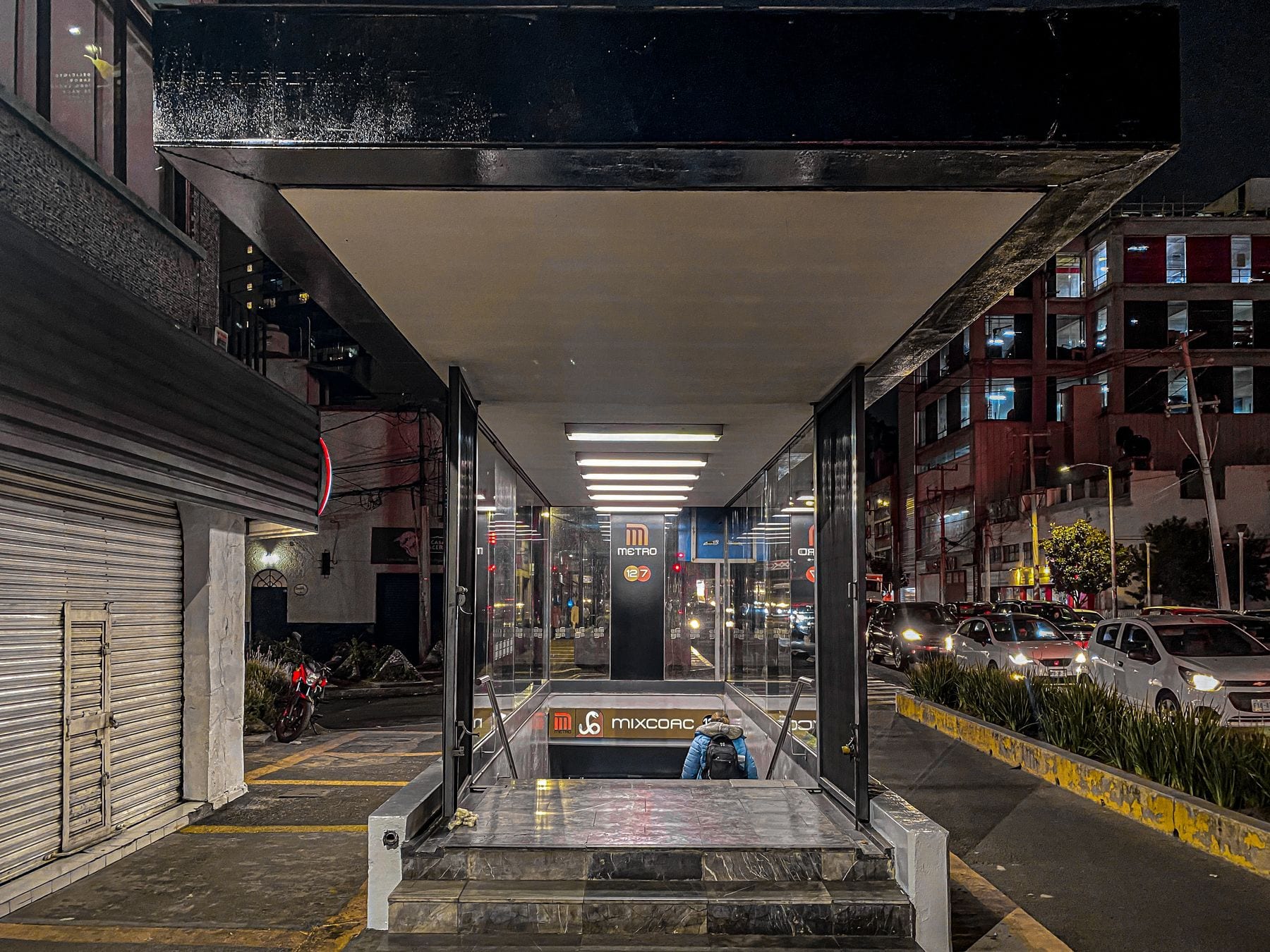 Entrada de la estación Mixcoac de la Línea 12 del Metro de la Ciudad de México, fotografiada de noche con el logotipo del Metro y el letrero de la estación sobre el acceso.