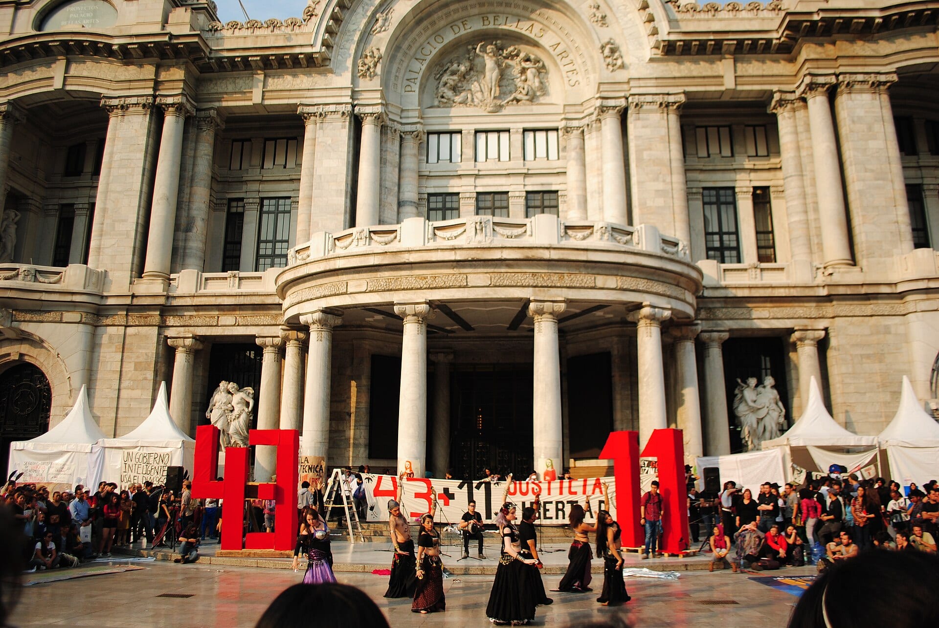 Un grupo de bailarinas actúa frente al Palacio de Bellas Artes junto a las cifras "43" y "11" en rojo y mantas con la consigna "Justicia y libertad", durante una conmemoración por Ayotzinapa.