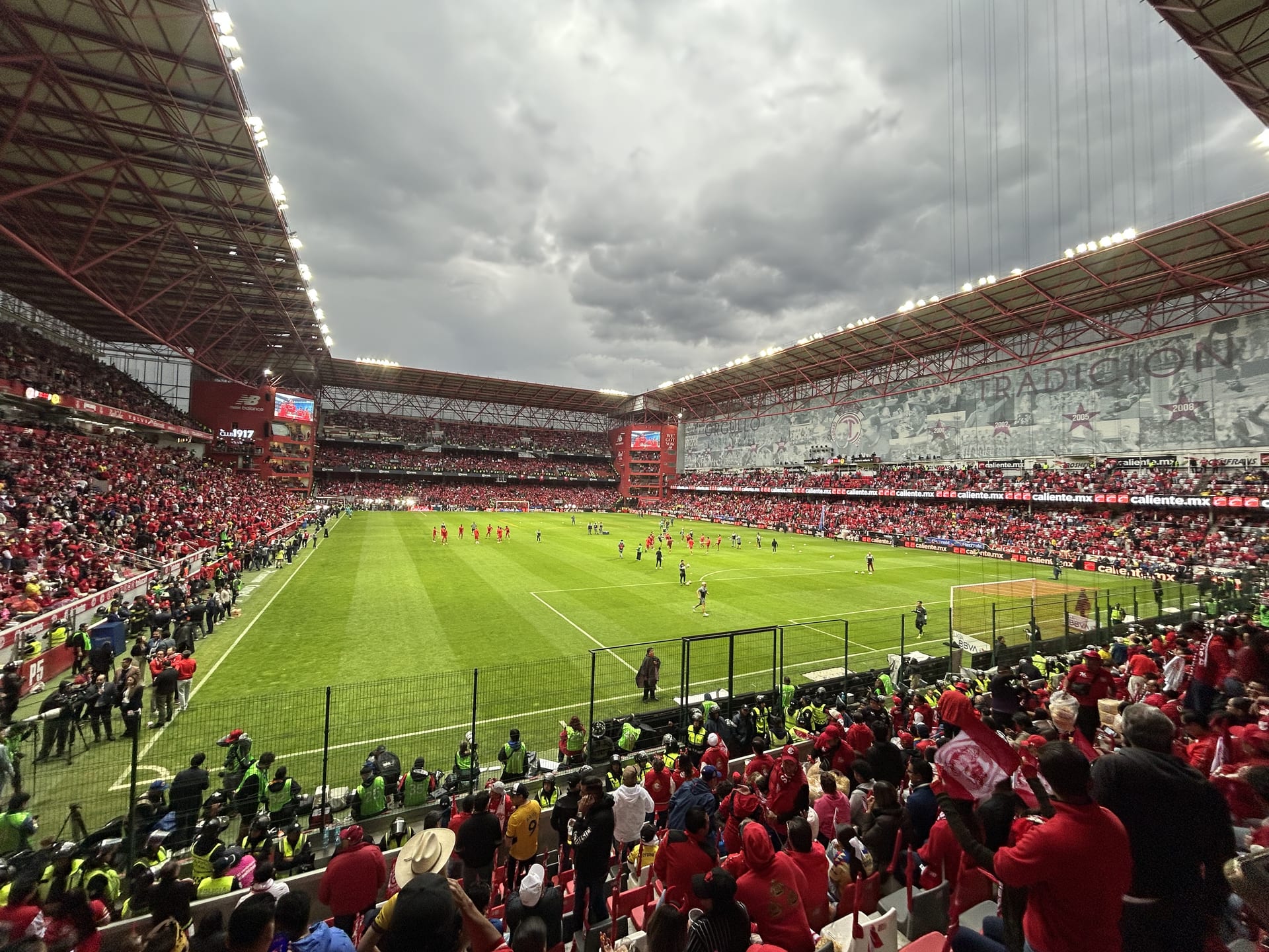 Vista general del Estadio Nemesio Díez lleno de aficionados vestidos de rojo, con el campo de juego al centro bajo un cielo nublado. Fotografía de archivo de otro partido en el mismo estadio.