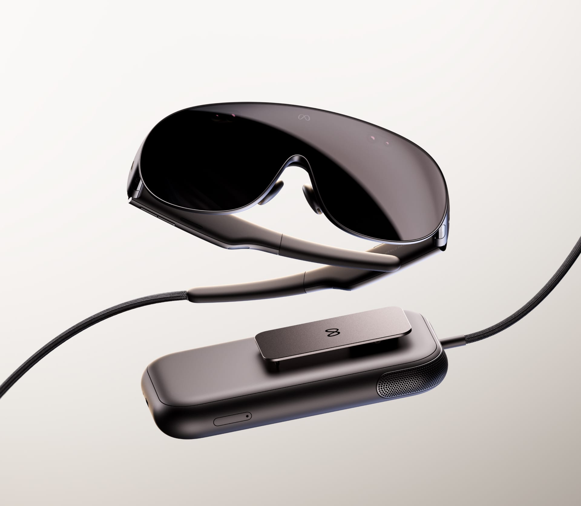 Primer plano de unas gafas delgadas de realidad virtual con montura de color claro sobre fondo oscuro.