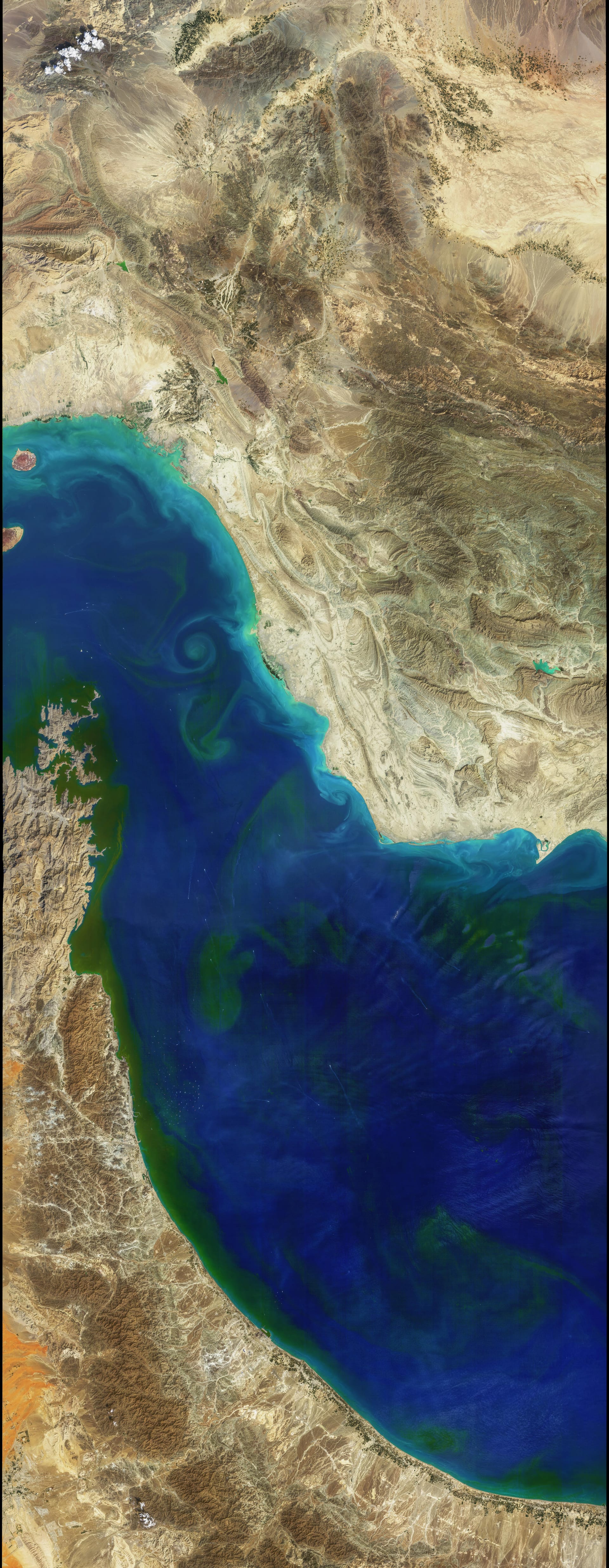 Vista satelital de remolinos turquesa y verde en las aguas del estrecho de Ormuz, entre la costa iraní y la arábiga.