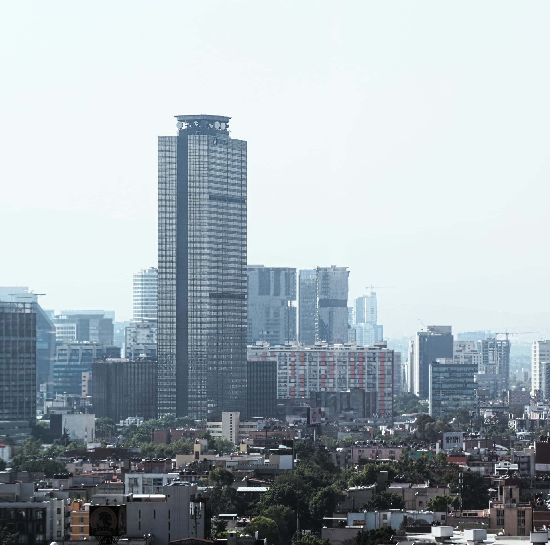 Torre alta de oficinas con el logotipo de Pemex en su fachada, vista desde una calle de la Ciudad de México.
