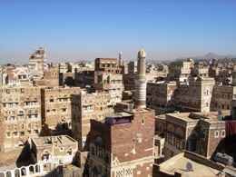 Vista panorámica de los tejados y minaretes de la ciudad vieja de Saná, con edificios de adobe decorado.