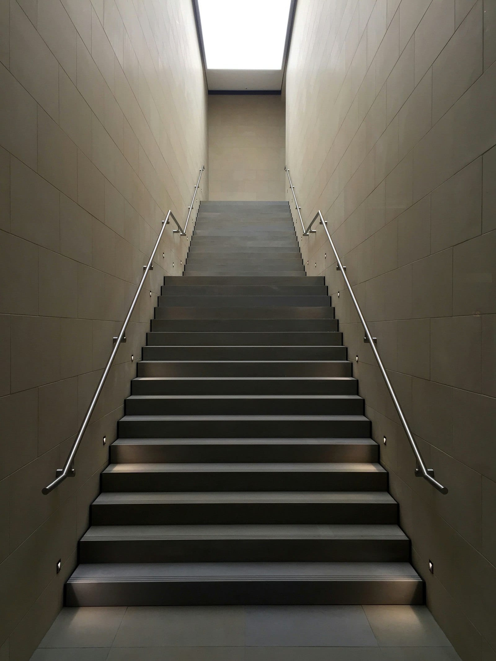 Escalera interior con barandales metálicos a los dos lados, vista de frente desde abajo.