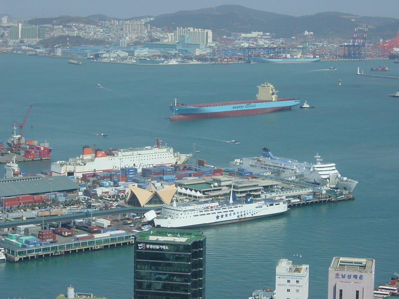 Vista panorámica del puerto de contenedores de Busan, Corea del Sur, con grúas y barcos de carga.