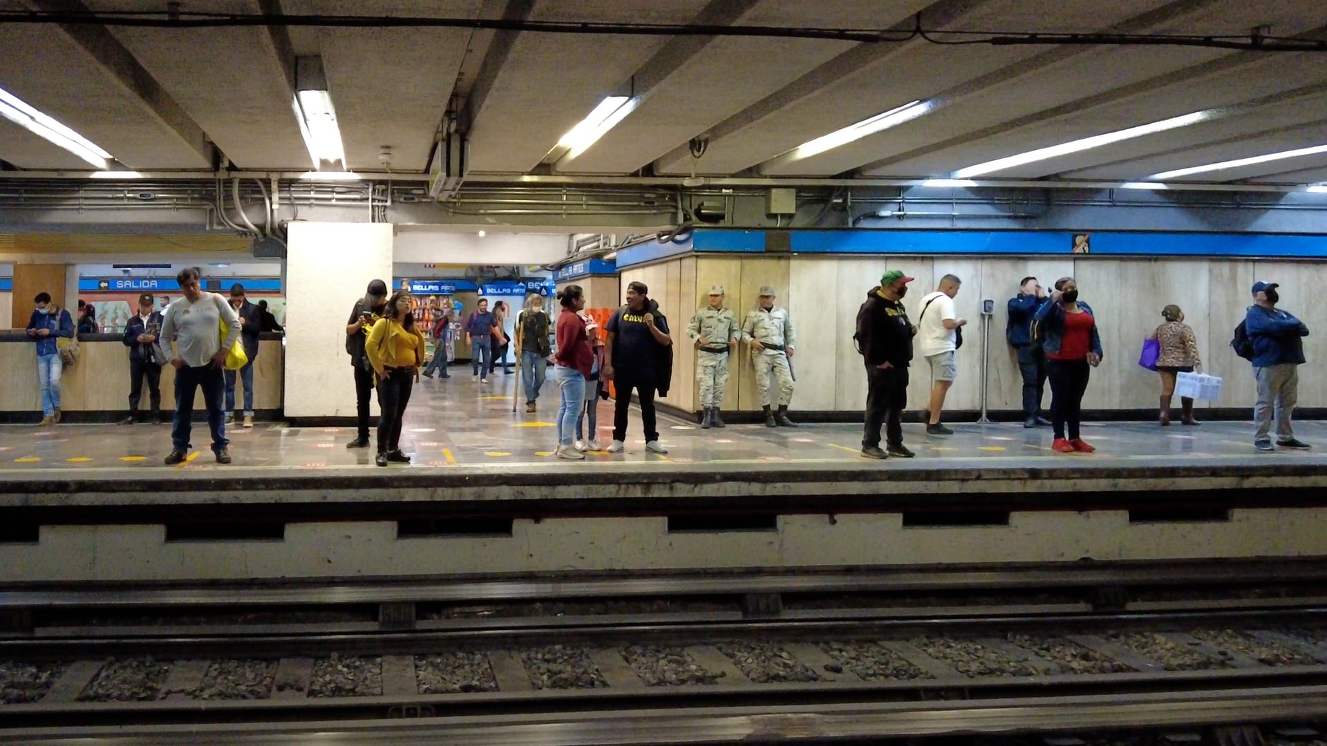 Dos elementos de la Guardia Nacional en uniforme camuflado permanecen de pie en el andén de una estación del Metro, entre pasajeros.