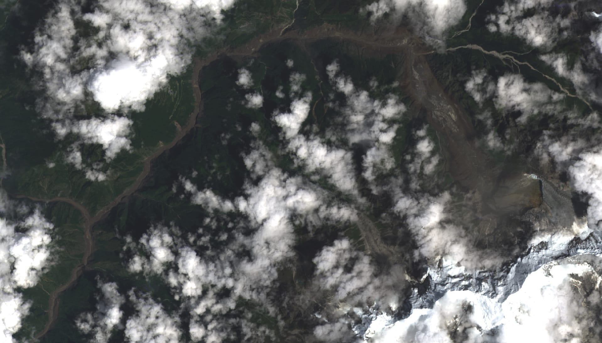 Imagen satelital que muestra el curso de un río ensanchado y sedimentos oscuros sobre un valle montañoso.