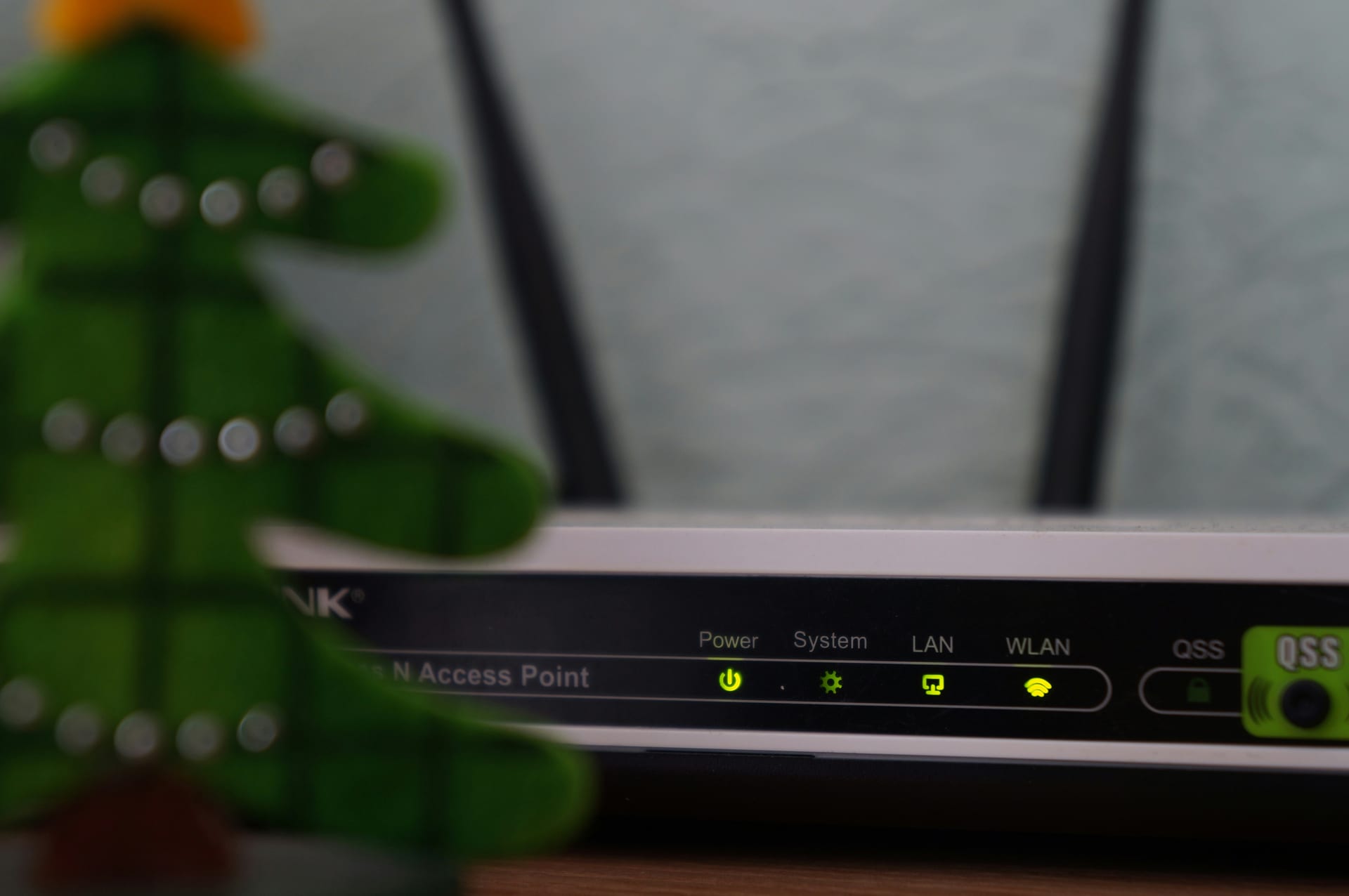 Un router con dos antenas y luces indicadoras verdes encendidas junto a las etiquetas Power, System, LAN y WLAN.