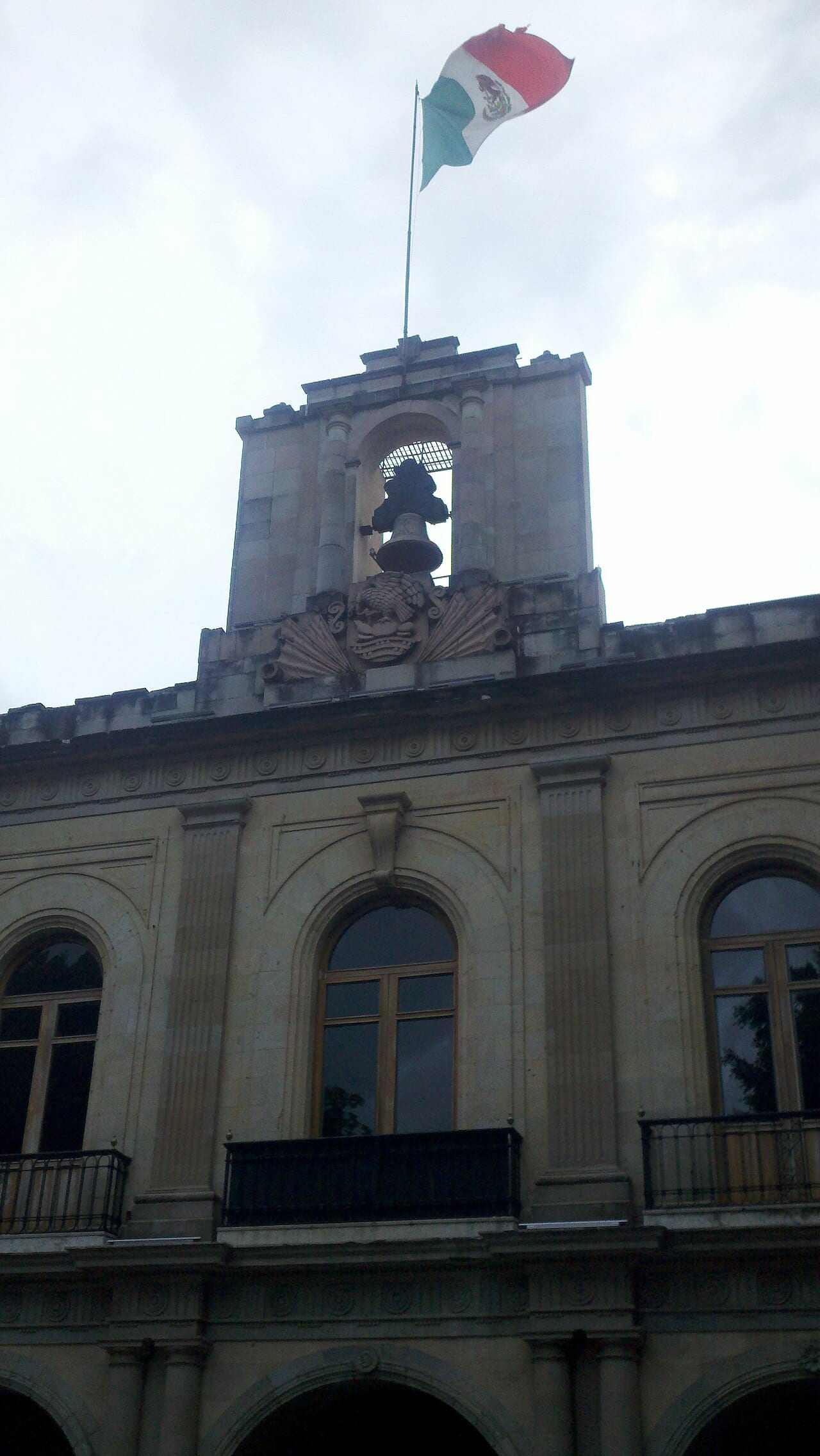 Campanario del Palacio de Gobierno de Oaxaca, con la bandera nacional ondeando en lo alto.
