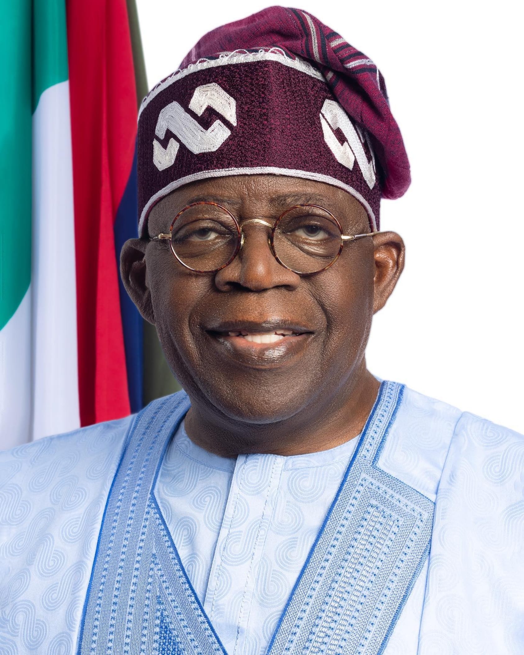 Retrato oficial del presidente de Nigeria, Bola Tinubu, con gorro tradicional y frente a las banderas del país.