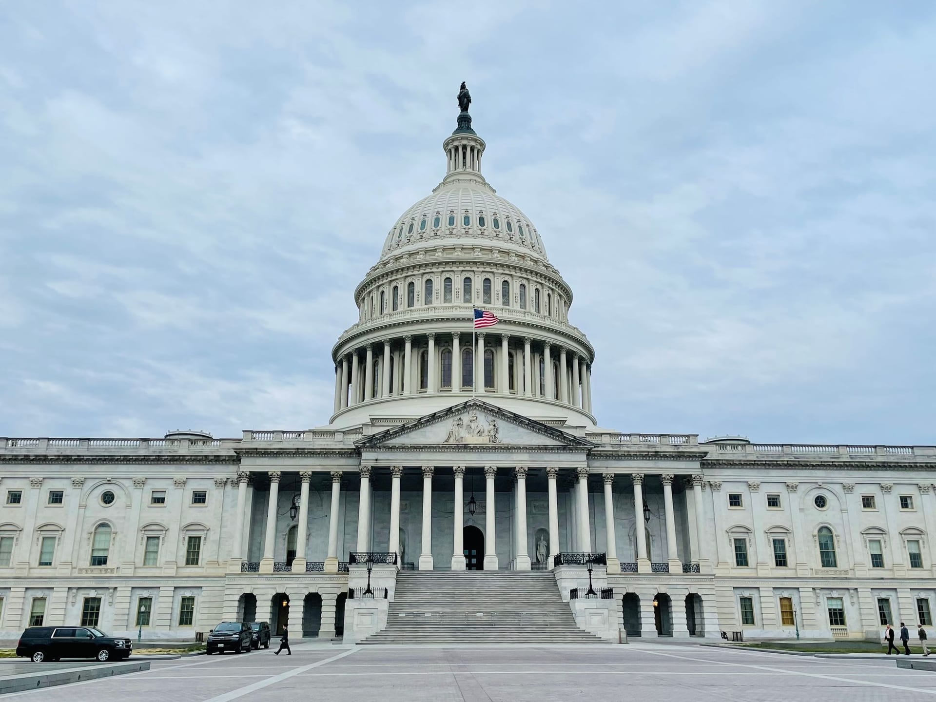 Vista frontal del Capitolio de Estados Unidos en Washington, con su cúpula blanca, la bandera ondeando y la escalinata de acceso.