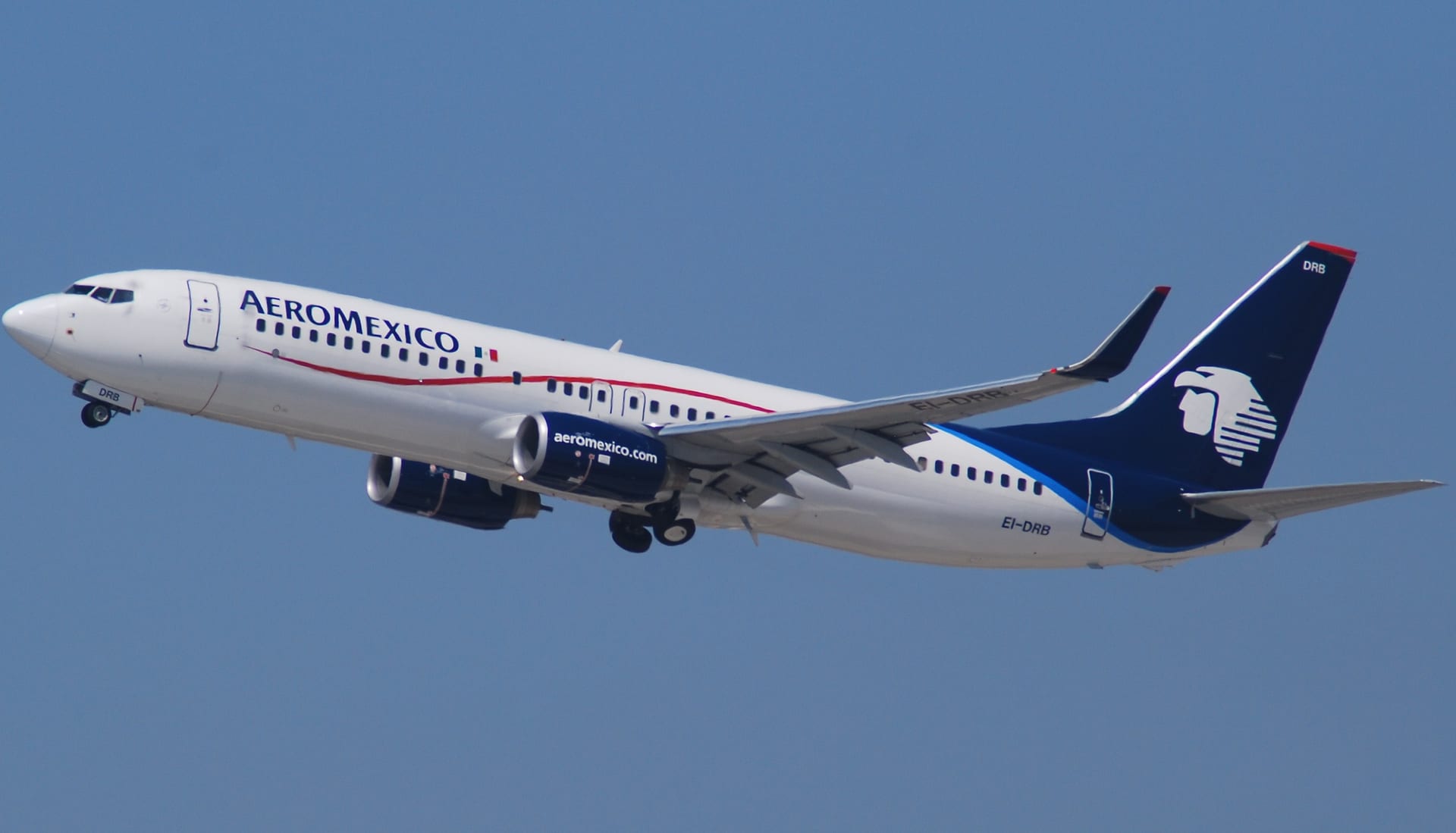 Un Boeing 737-800 con la librea de Aeroméxico asciende con el tren de aterrizaje extendido sobre un cielo despejado.