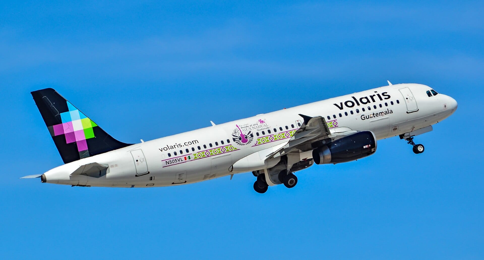 Un avión Airbus A320 con la librea de Volaris asciende tras el despegue, con el tren de aterrizaje extendido.