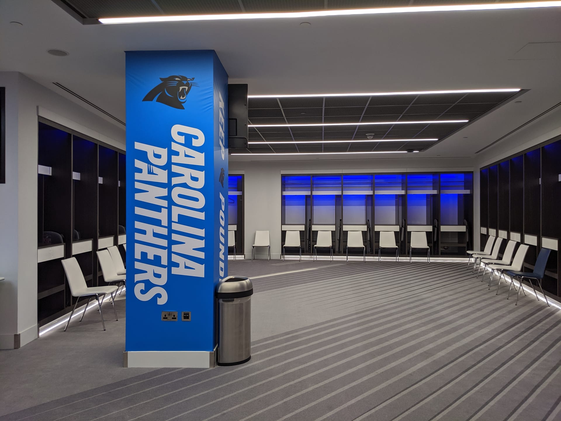 El nombre y el logotipo de los Carolina Panthers pintados sobre una columna azul en un vestidor de visitantes.