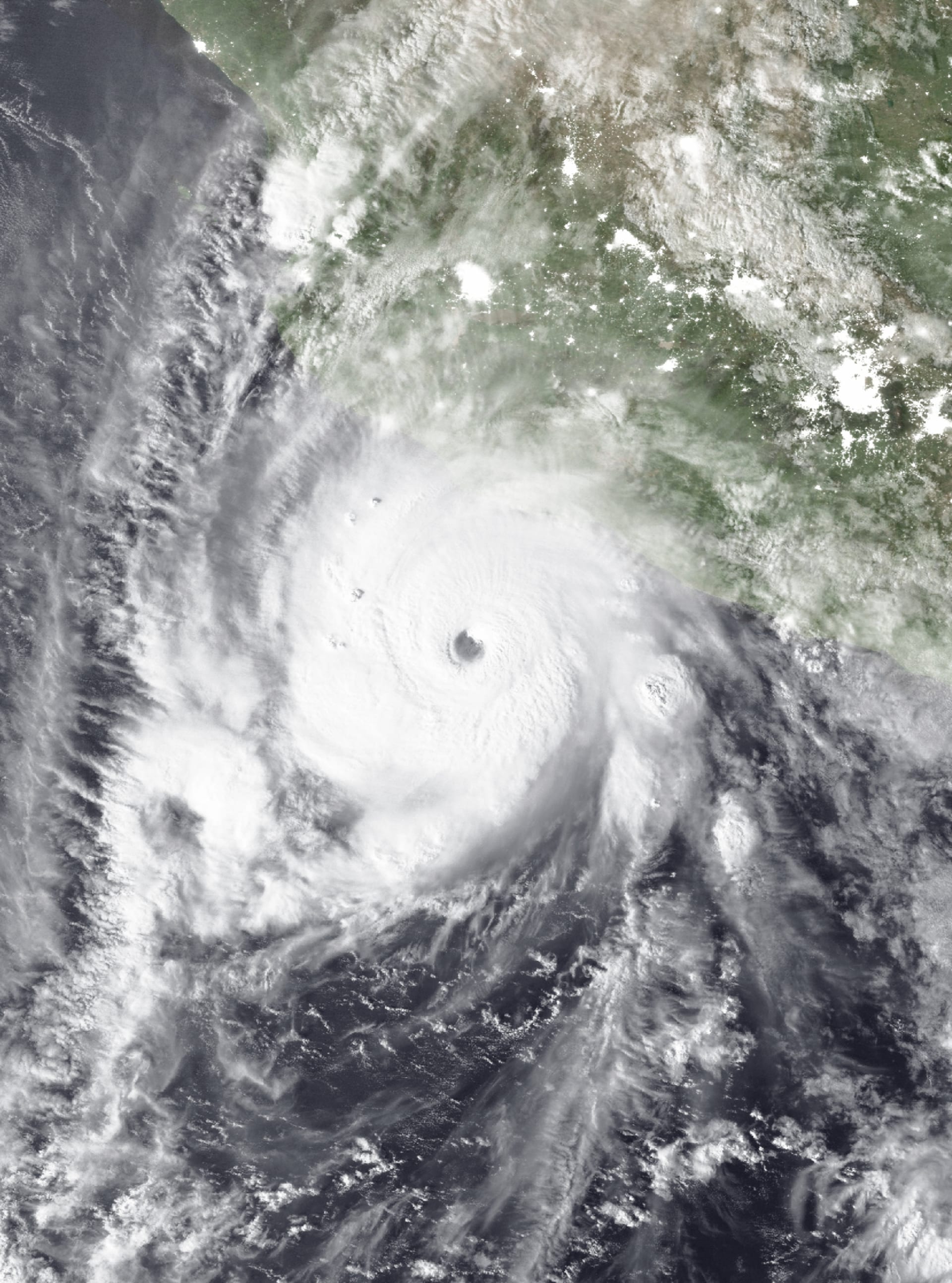 Imagen satelital en color natural muestra el ojo bien definido del huracán Polo frente a la costa del Pacífico mexicano, con la línea de costa visible en la parte superior del cuadro.