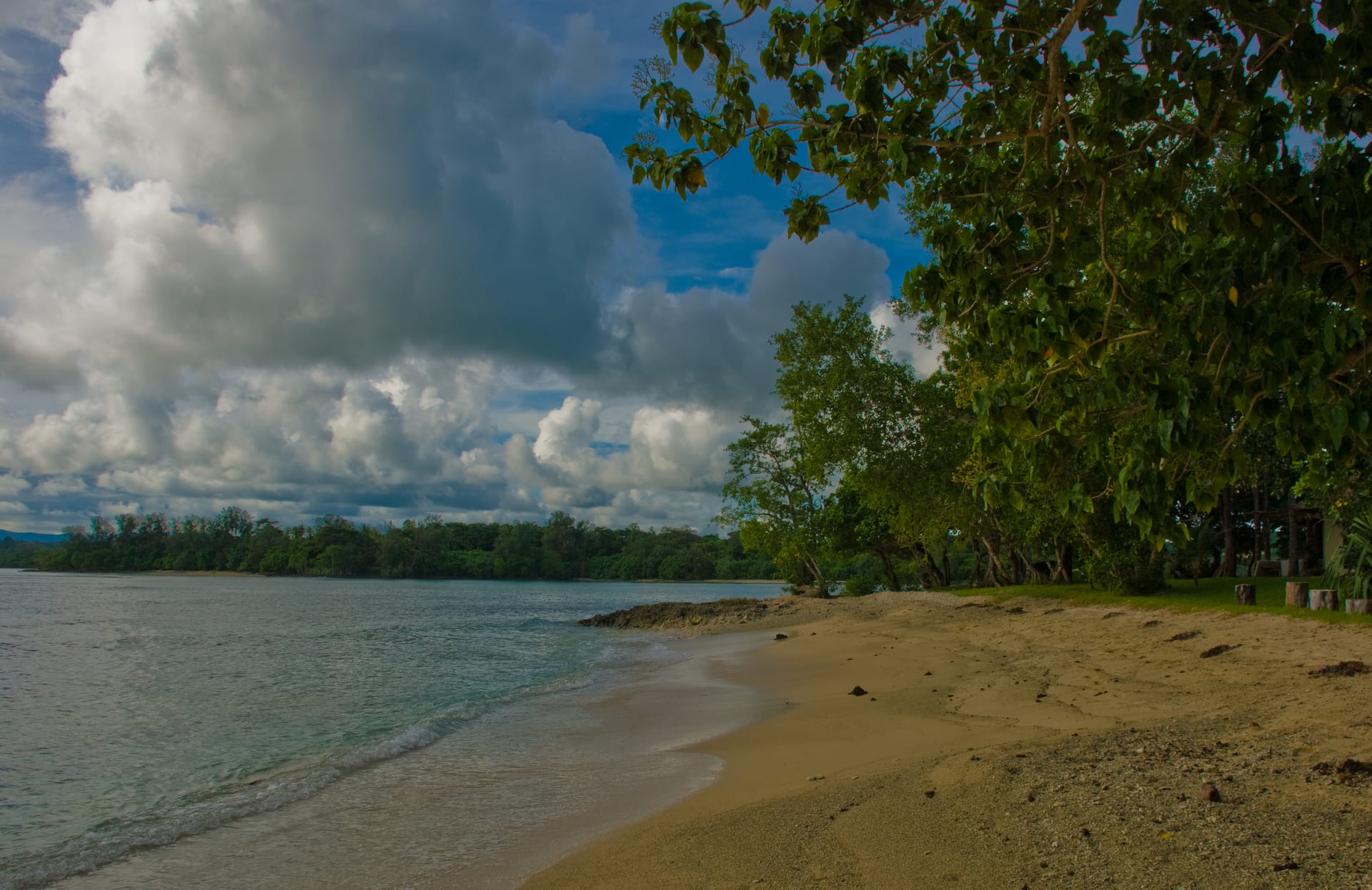 Playa vacía de arena clara y agua turquesa en calma, bajo un cielo nublado, en una laguna de Vanuatu.