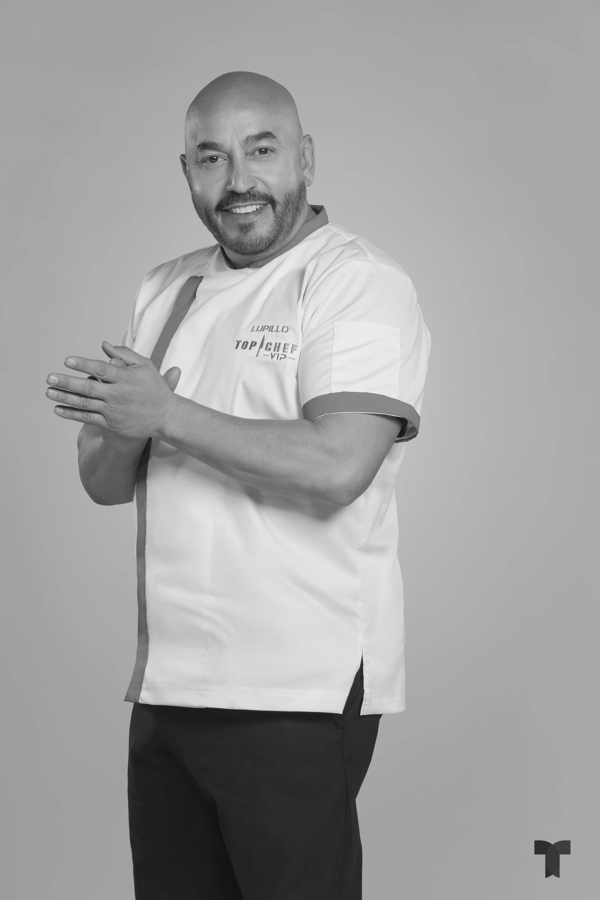 Retrato de estudio de un hombre con sombrero de vaquero y traje de chef color vino, con los brazos cruzados.