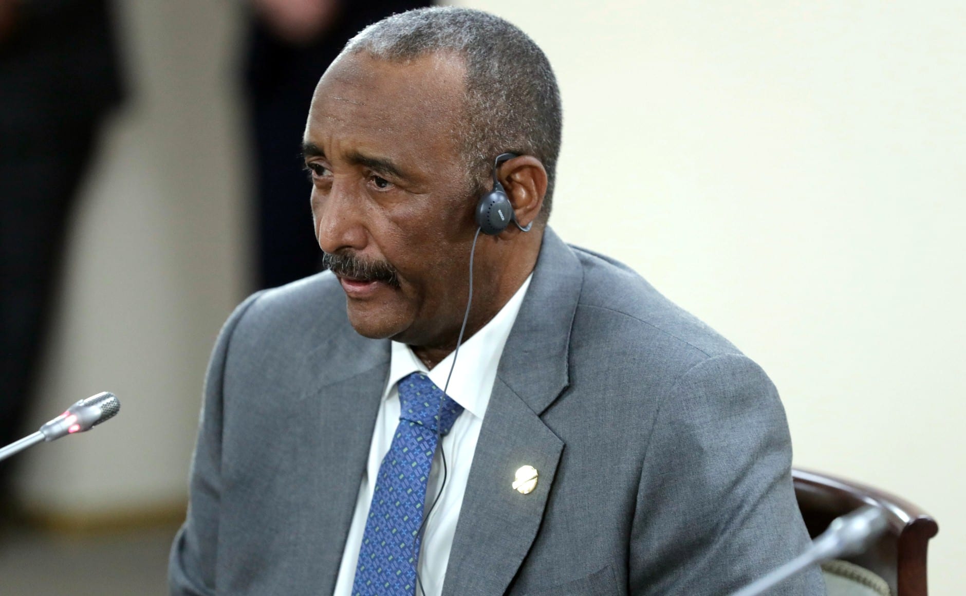 Abdel Fattah al Burhan, con auriculares de interpretación, sentado ante un micrófono en una sala de reuniones formal.