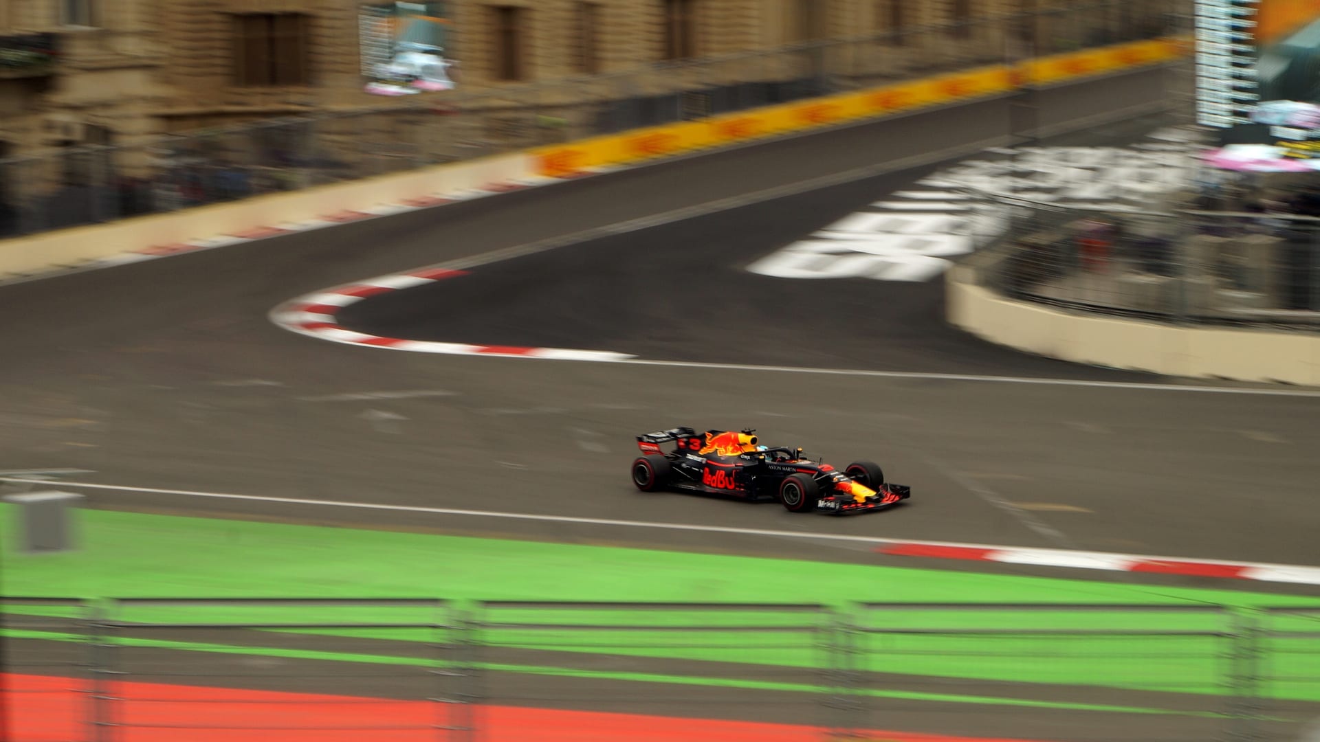 Un monoplaza con librea de Red Bull toma una curva del circuito callejero de Bakú, junto a edificios históricos de la ciudad.