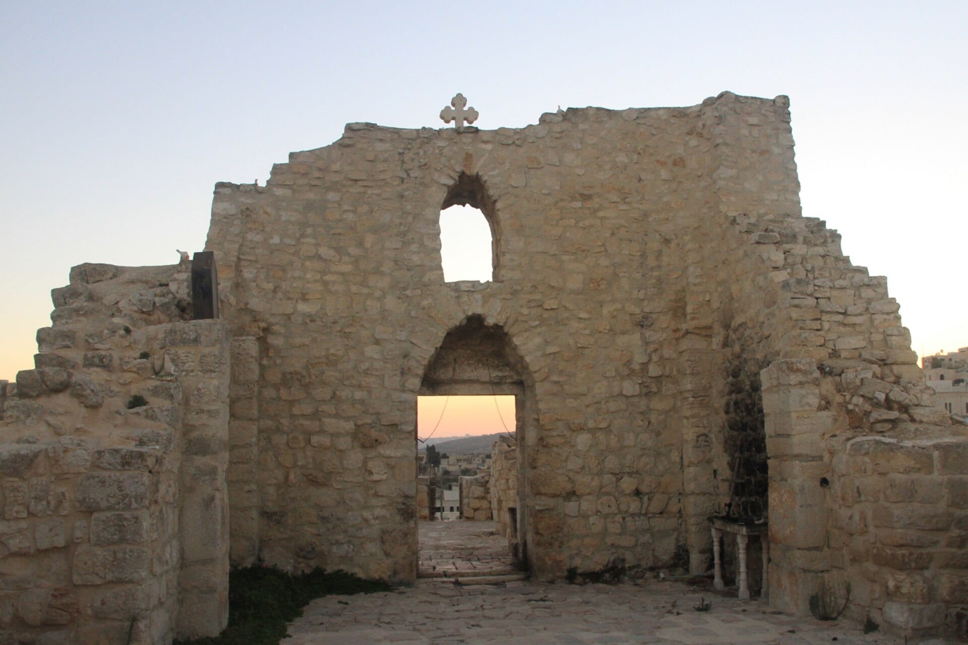 Fachada en ruinas de una iglesia de piedra con un arco de acceso, en el pueblo de Taybeh, en Cisjordania.