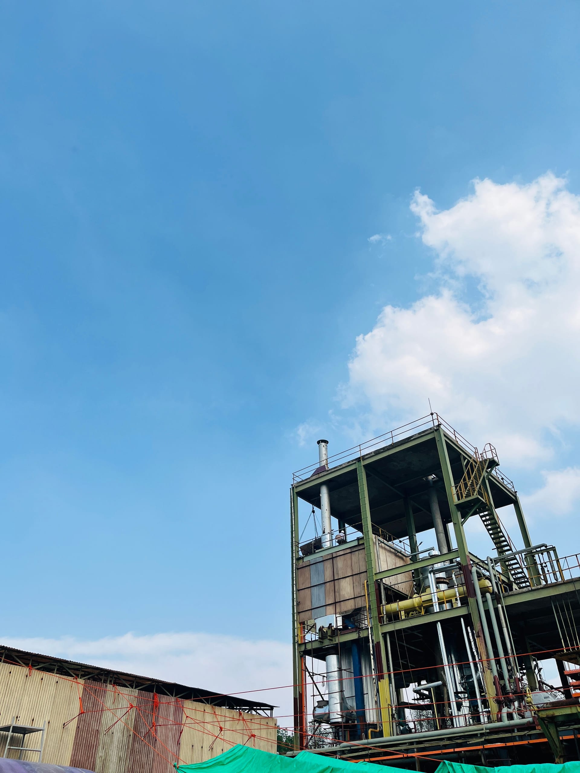 Una nave industrial de gran tamaño con techo metálico y chimeneas, bajo un cielo despejado.