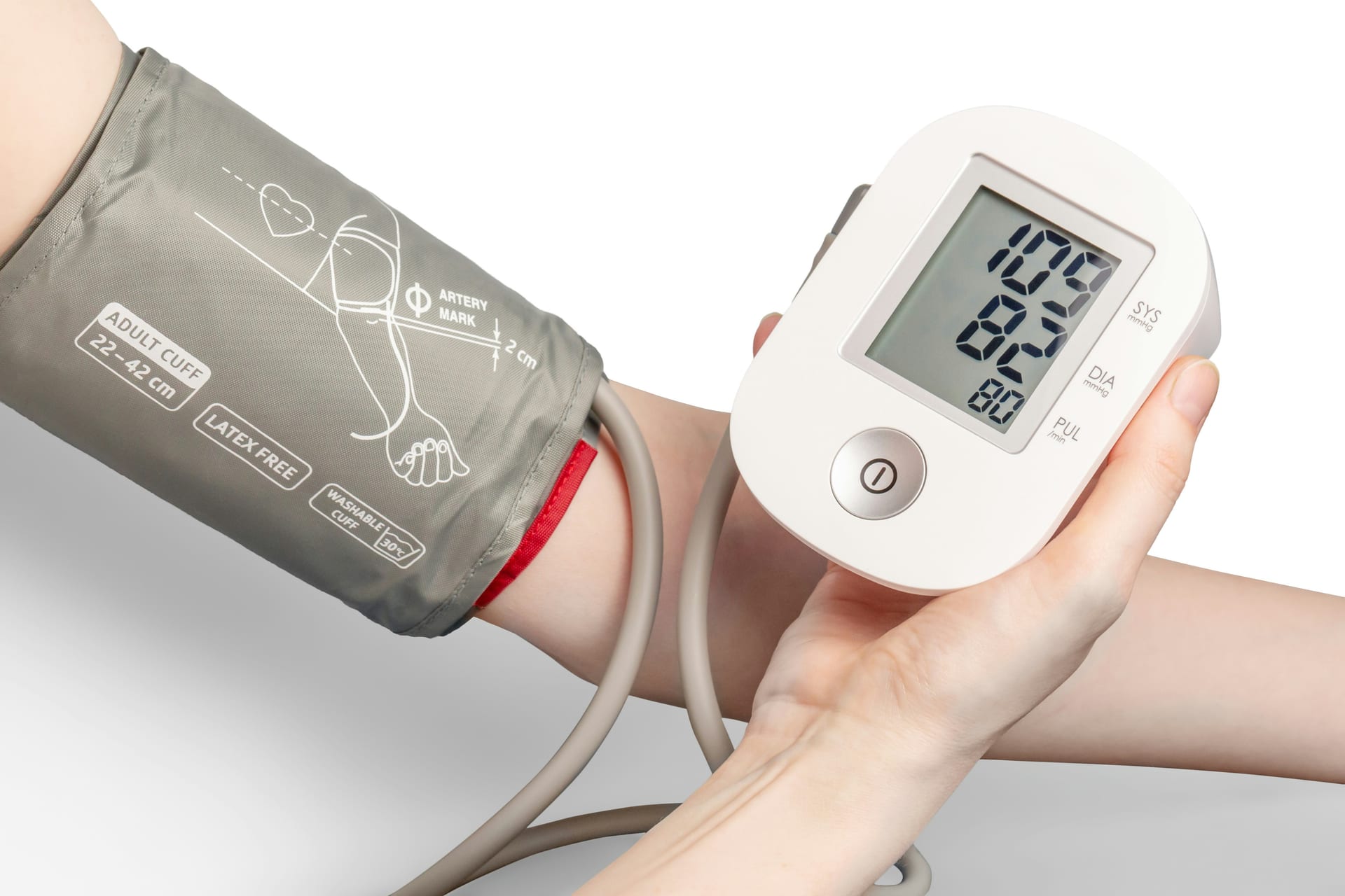 Una persona sostiene un monitor digital de presión arterial con el brazalete puesto en el antebrazo.