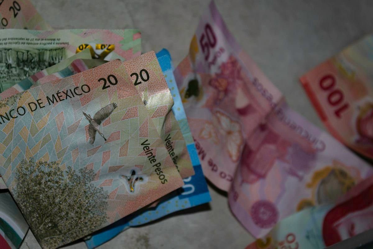 Billetes mexicanos de distintas denominaciones, arrugados, sobre una superficie de concreto.