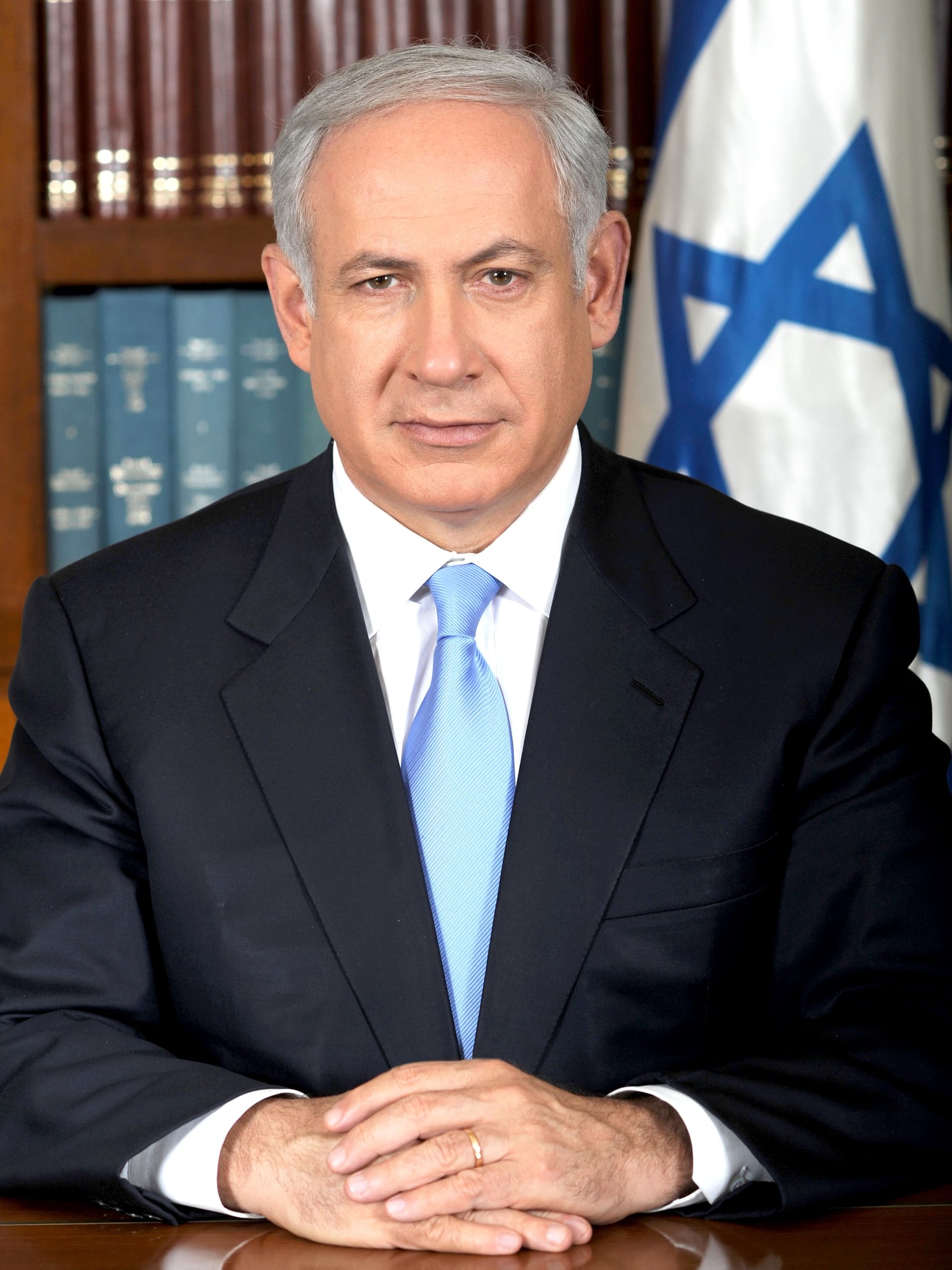 Benjamín Netanyahu, de traje oscuro, mira de frente en un retrato oficial ante un fondo neutro.