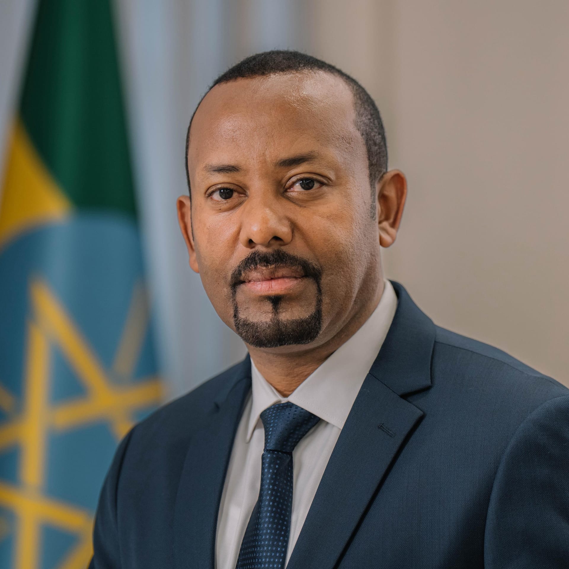 El primer ministro etíope Abiy Ahmed, de traje oscuro, posa de frente ante un fondo neutro.