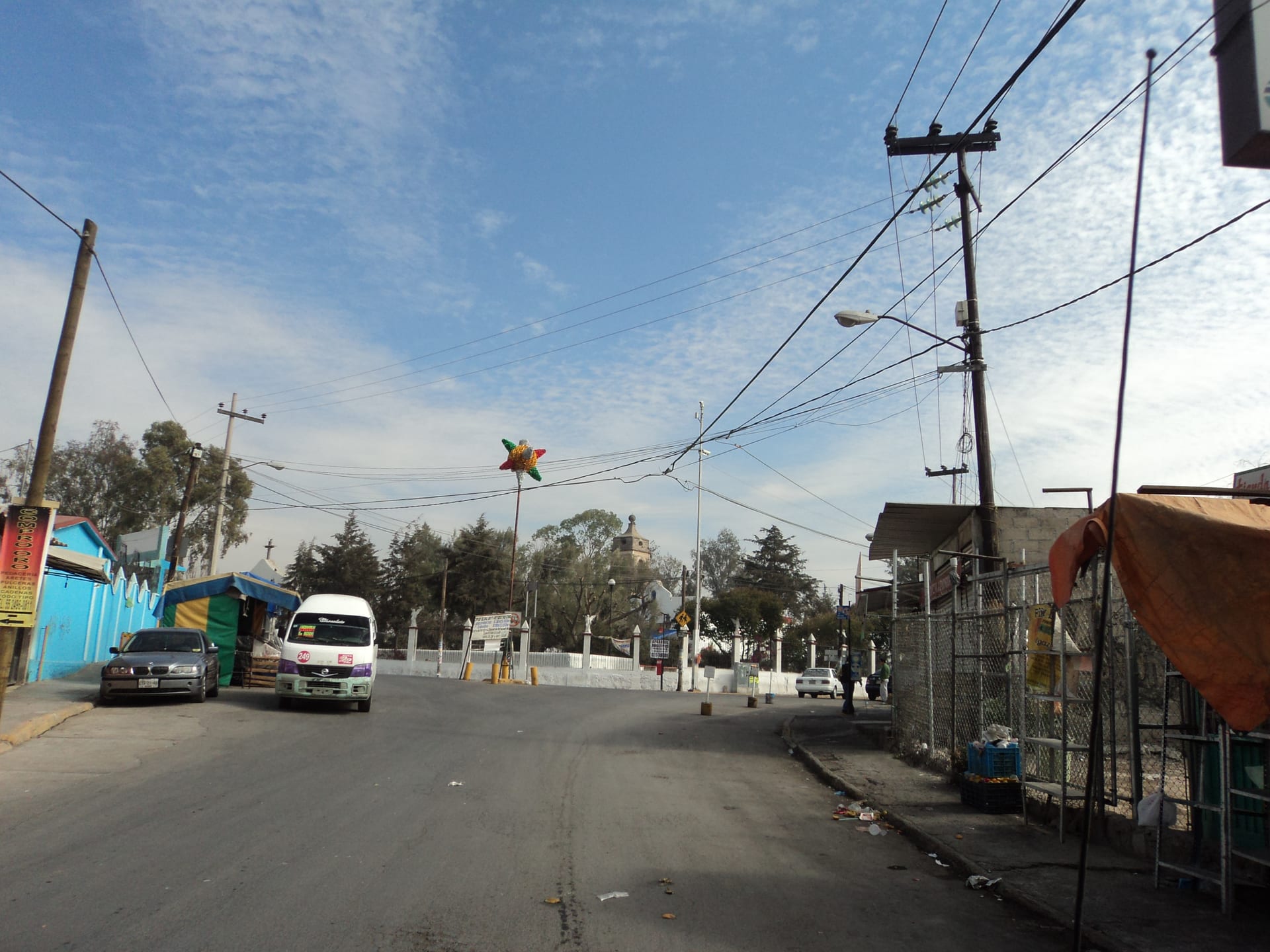 Una calle de San Francisco Tepojaco, en Cuautitlán Izcalli, con comercios, un microbús y cableado eléctrico sobre la vía.