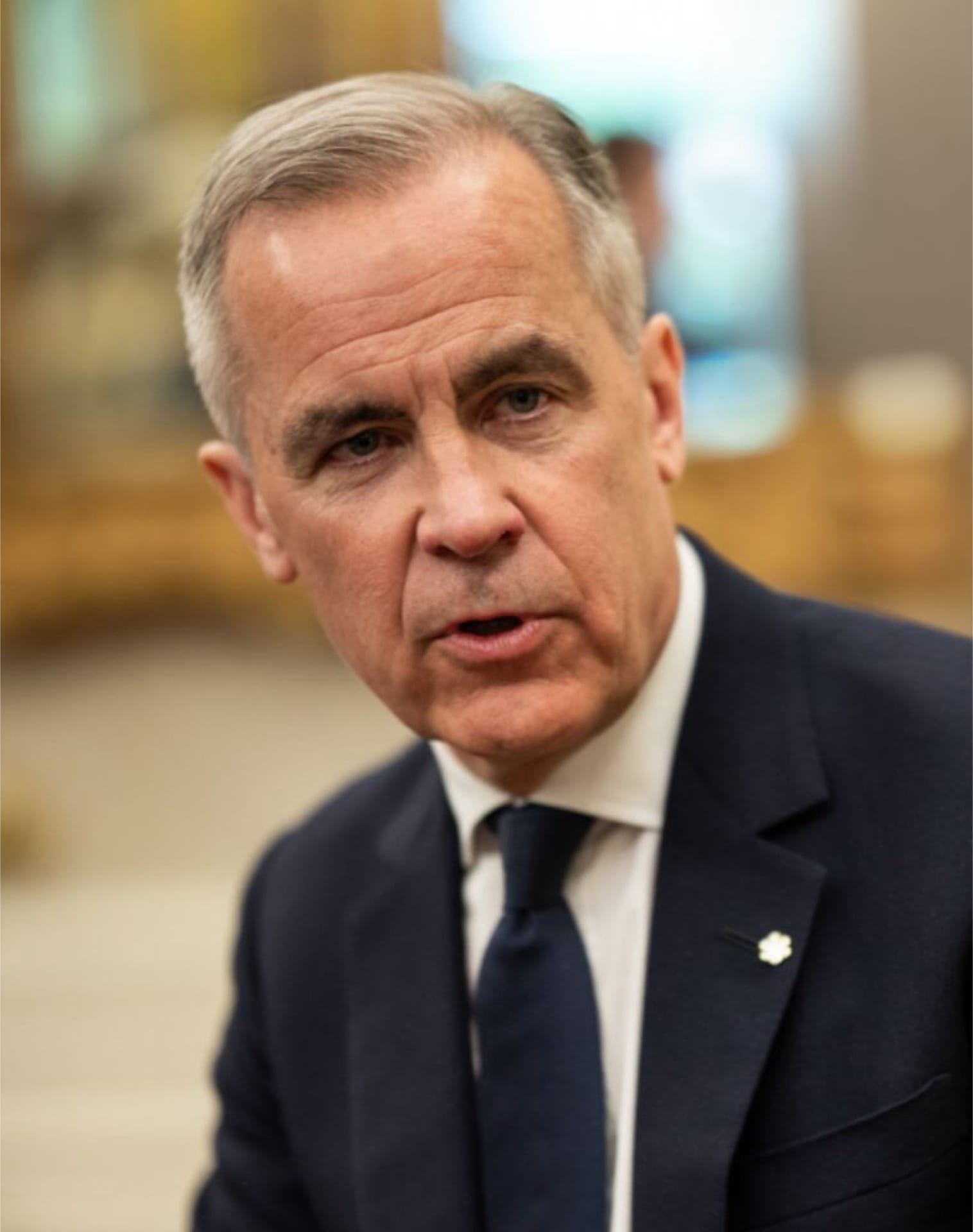 Mark Carney, de cabello canoso y traje oscuro con corbata azul marino, habla mirando hacia la cámara.