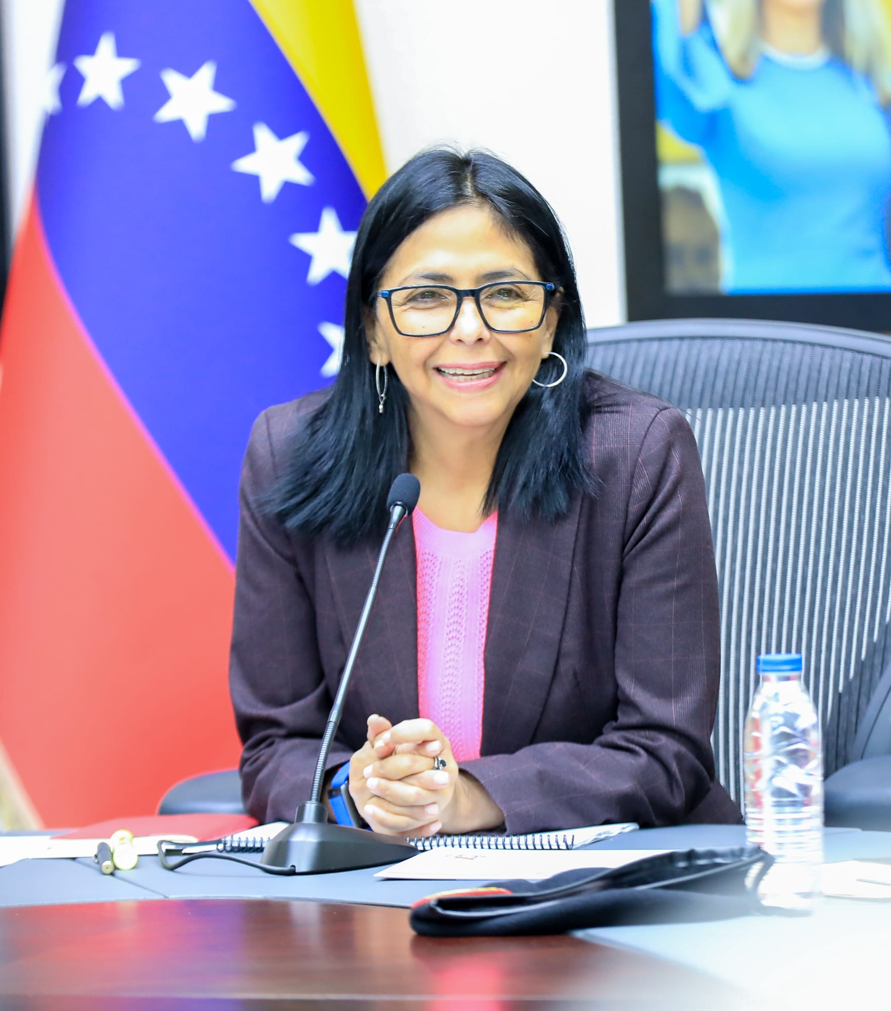 Delcy Rodríguez, con traje formal, habla ante un atril con micrófonos frente a ella.