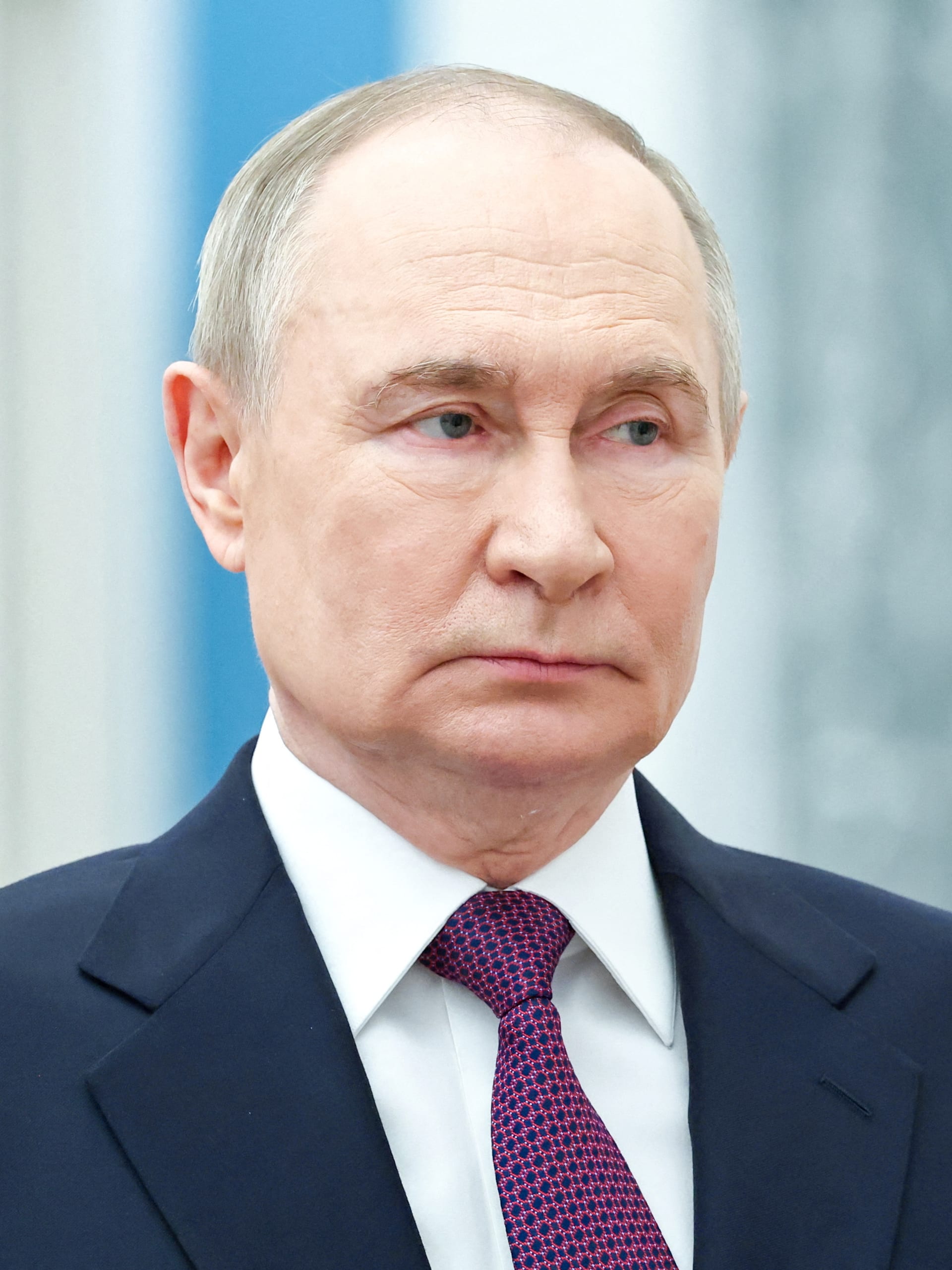 Vladímir Putin, con gesto serio, sentado frente a una bandera con el escudo de Rusia.