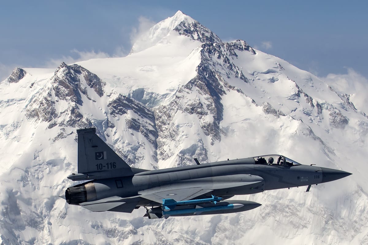 Un caza JF-17 de la Fuerza Aérea de Pakistán vuela armado frente a una cordillera nevada.