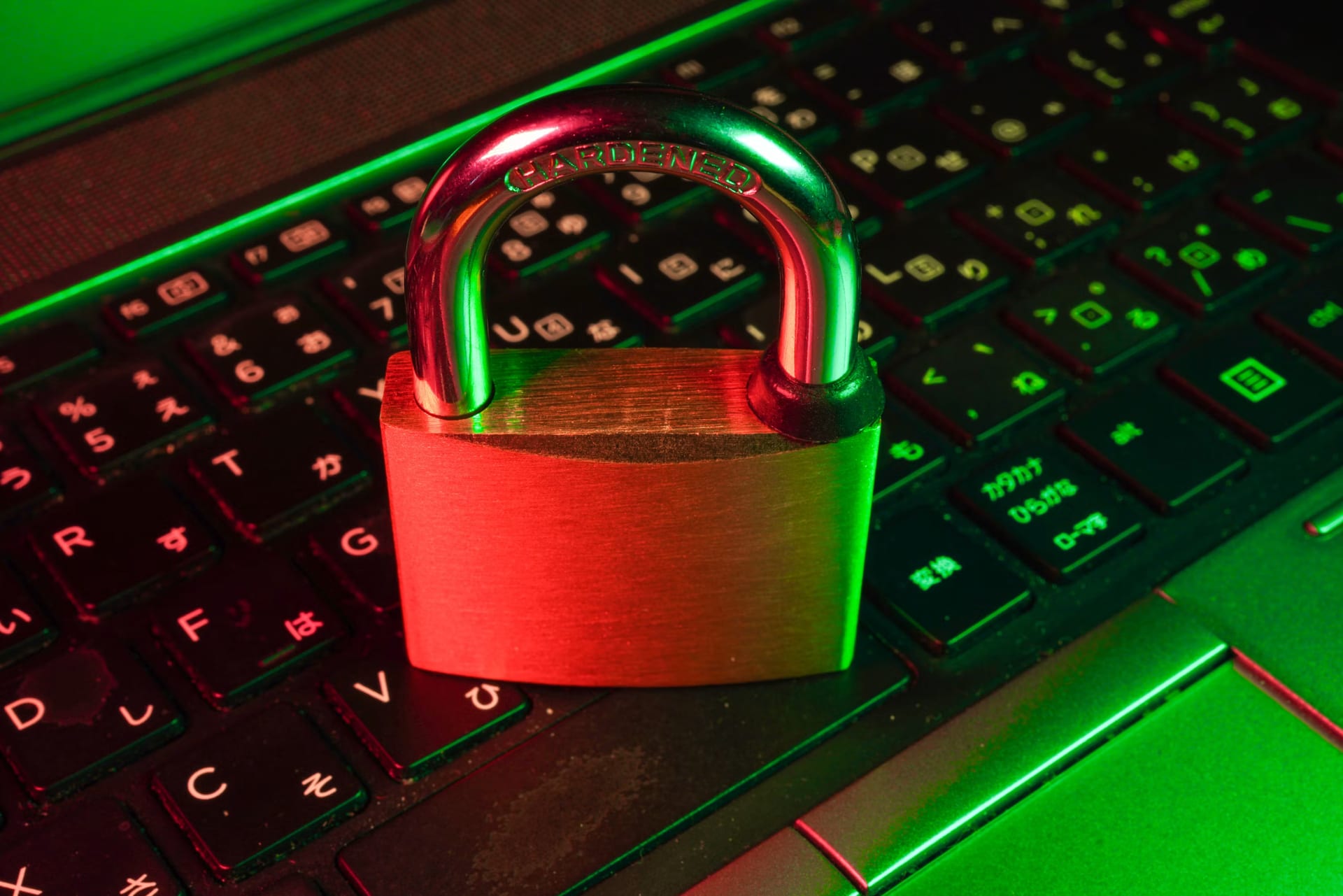 Un candado rojo iluminado descansa sobre las teclas oscuras de un teclado de computadora.