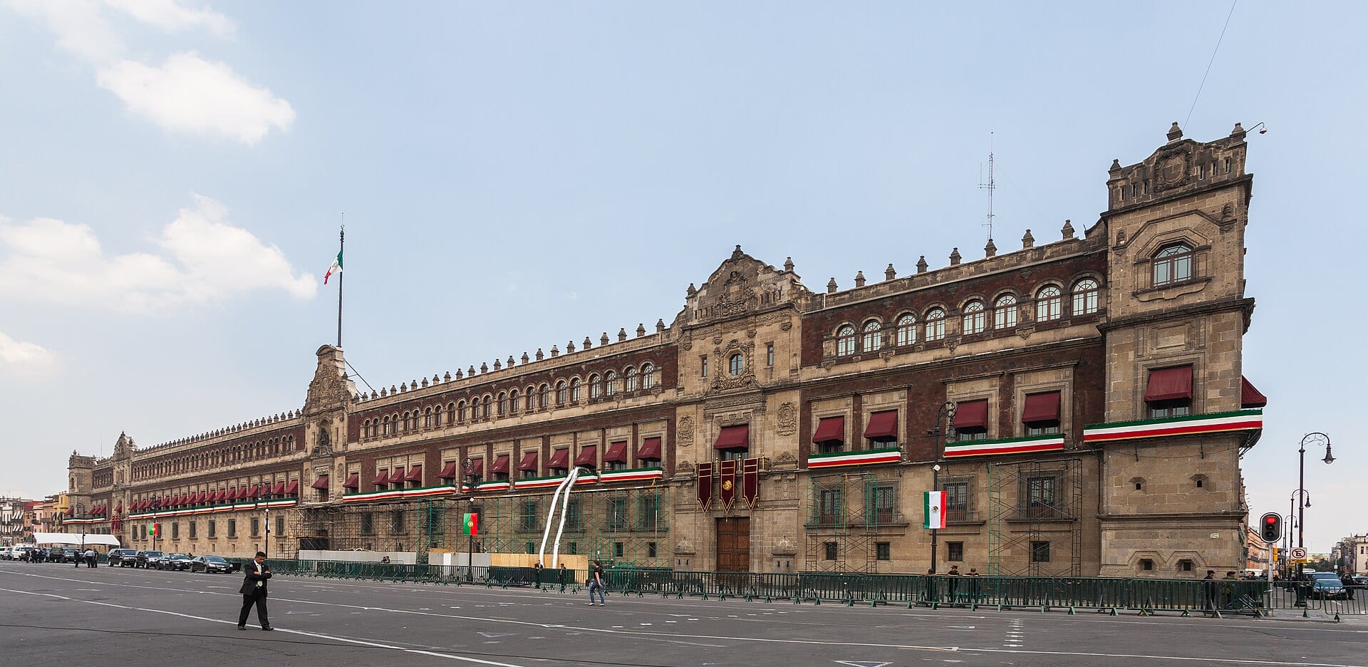 Fachada principal del Palacio Nacional de México, con arcos de cantera, balcones con listones tricolores y la bandera nacional en la azotea.