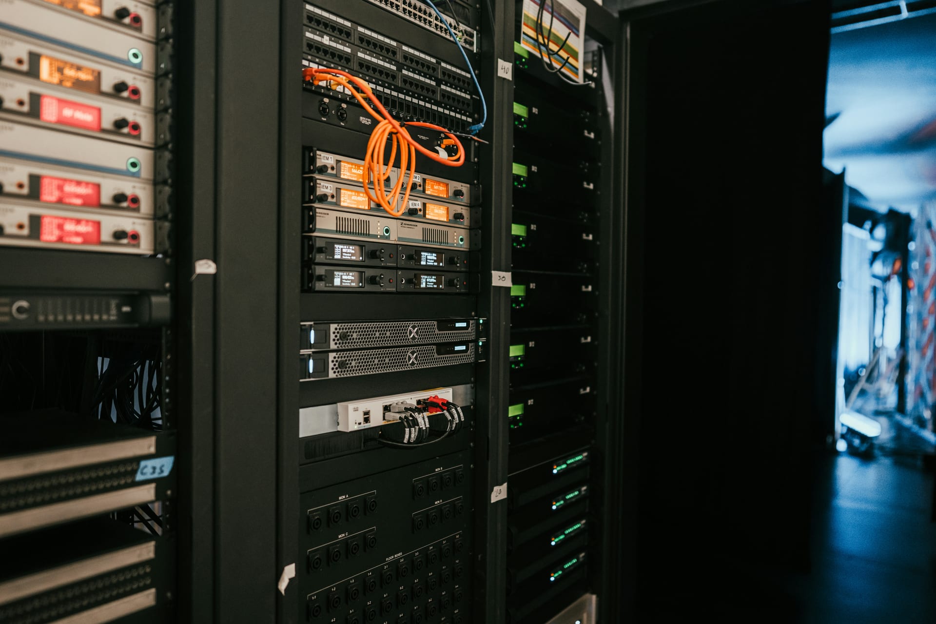 Una hilera de servidores en rack dentro de un centro de datos, con múltiples cables conectados en la parte frontal.