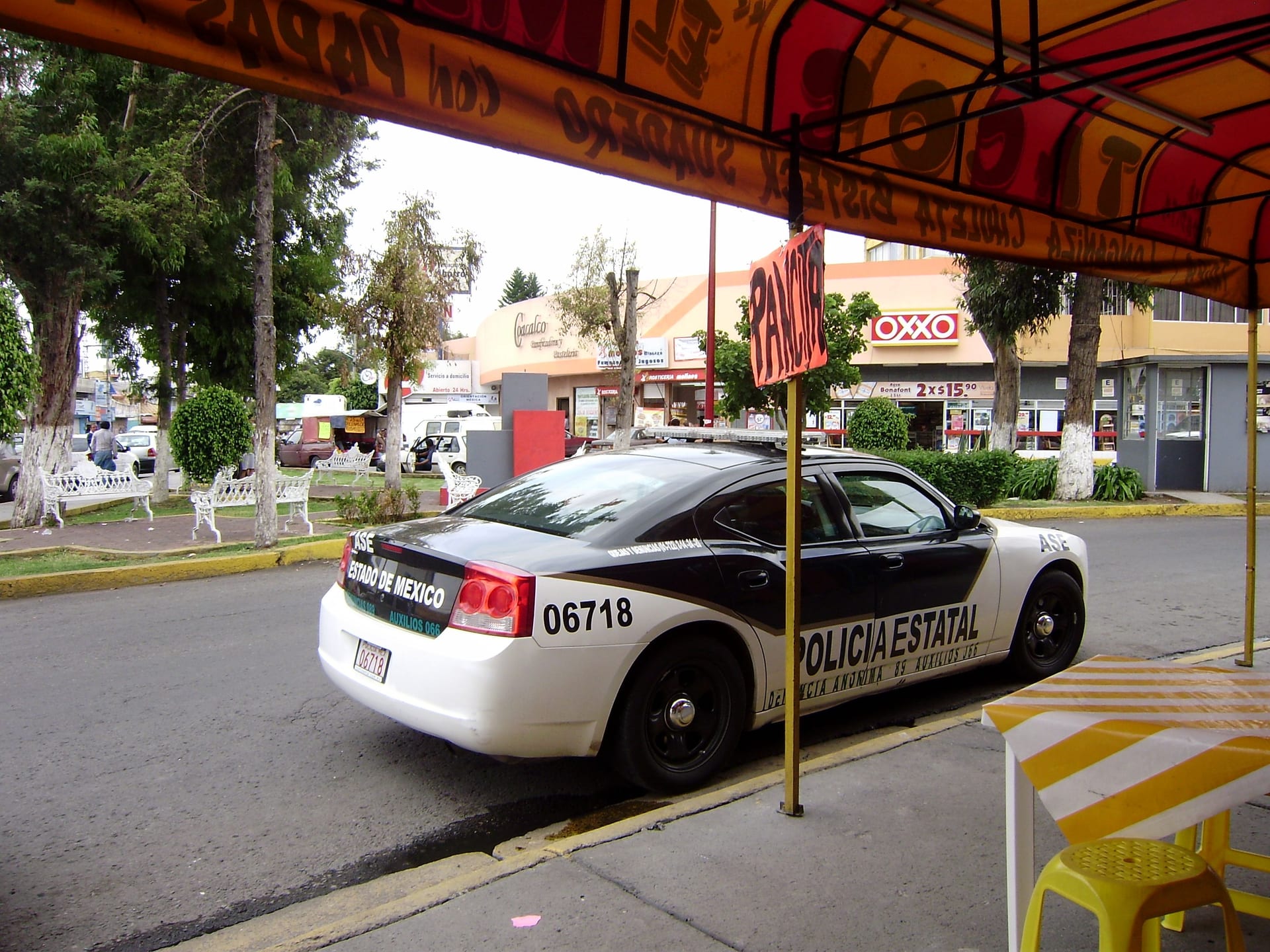 Una patrulla de la Policía Estatal del Estado de México, blanco y negro, estacionada en una calle comercial.