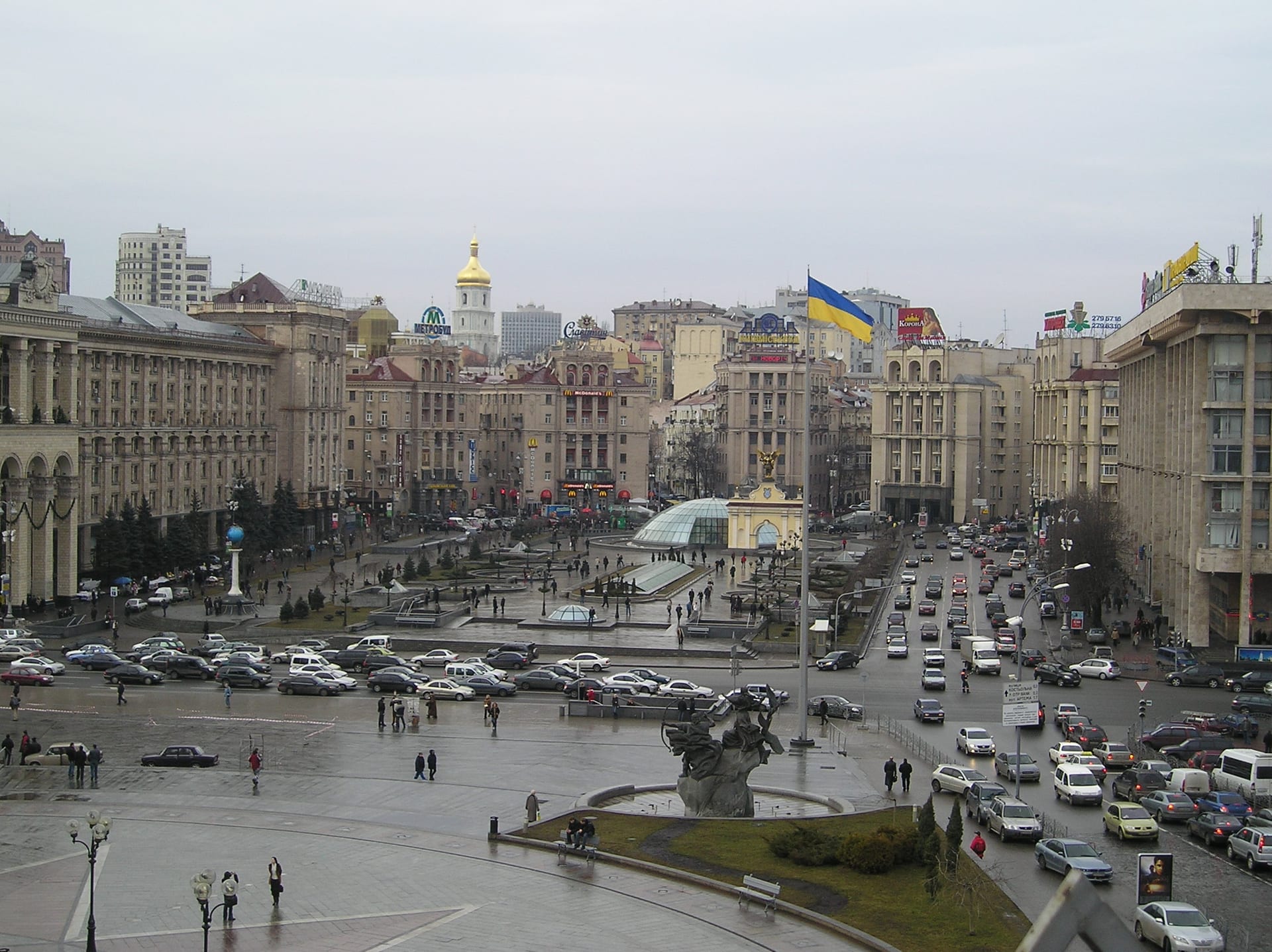 Vista de la plaza Maidán Nezalézhnosti en Kiev, con la bandera de Ucrania al centro y tráfico en las avenidas circundantes.