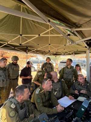 Varios oficiales militares uniformados de pie junto a un vehículo durante una evaluación de la situación tras el tiroteo.