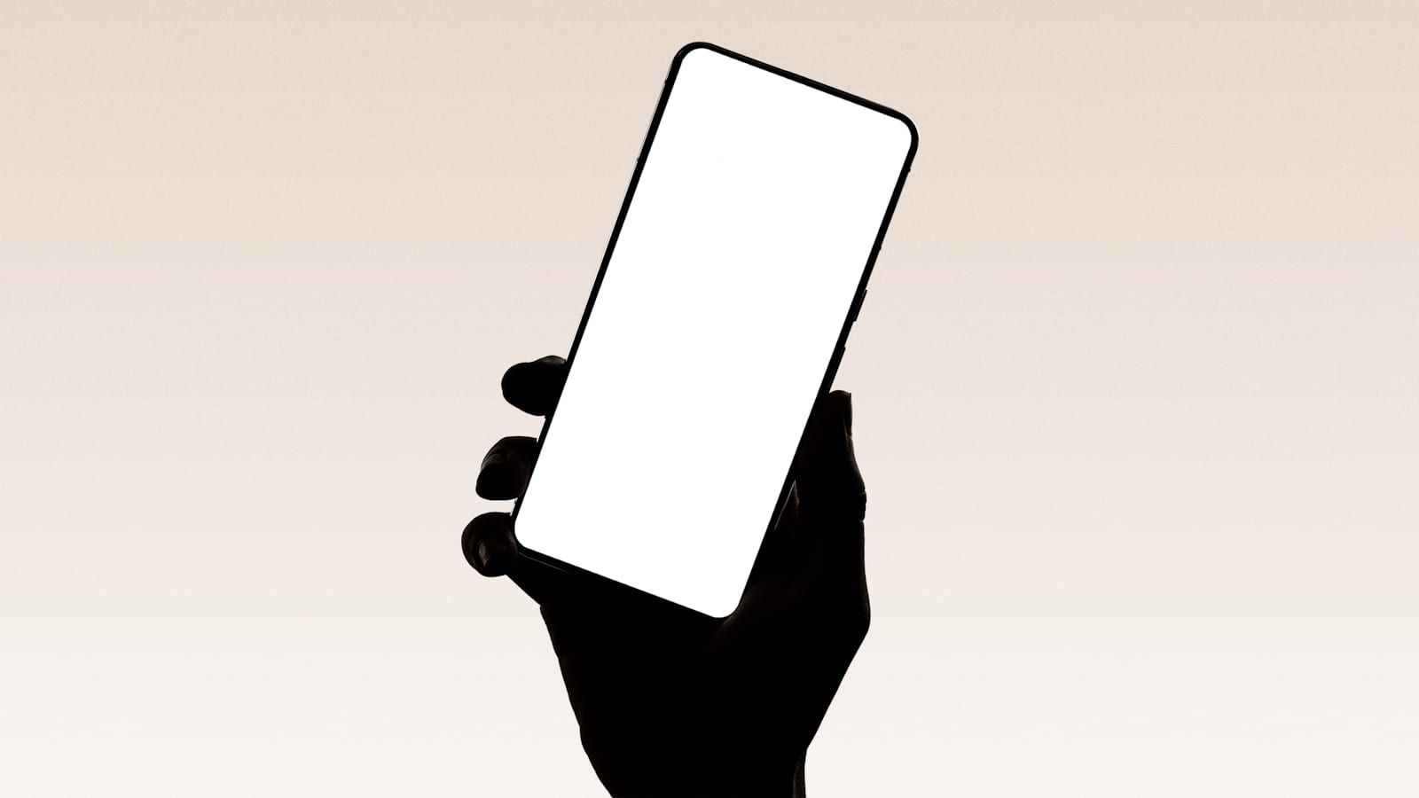 La silueta de una mano sostiene a contraluz un teléfono inteligente con la pantalla en blanco encendida.